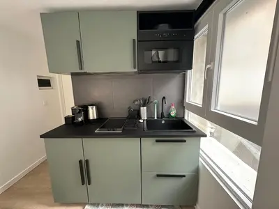 a kitchen with white cabinets and a sink and a window at Ixelles - Cozy studio in middle of European District in Brussels