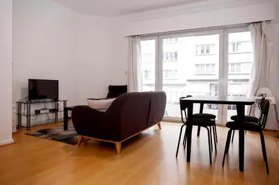a living room with a table and a chair and a couch at Appartement, deux chambres au pied du métro Montgomery in Brussels