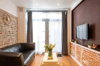 a living room with a leather couch and a tv at ETTERBEEK - Sunny loft Studio - EU AREA in Brussels