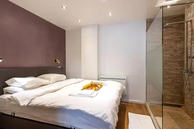 a bedroom with a large bed and a glass shower at ETTERBEEK - Sunny loft Studio - EU AREA in Brussels