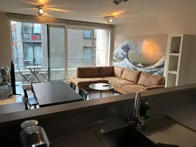 a living room with a couch and a large wave painting at Comfortable Two bedroom Apartment in City Center in Brussels