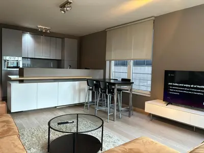 a living room with a table and a kitchen at Comfortable Two bedroom Apartment in City Center in Brussels