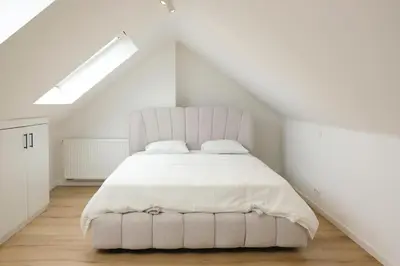a white bedroom with a large bed in a attic at Blu shell house in Brussels