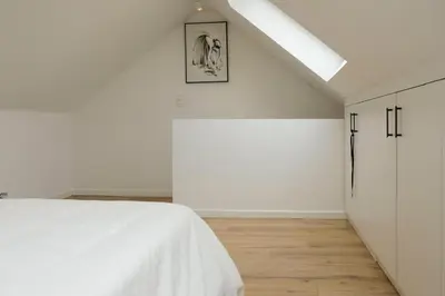 a white bedroom with a bed and a skylight at Blu shell house in Brussels