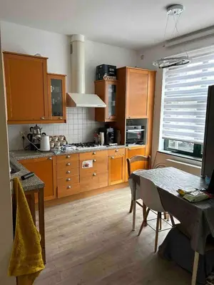 a kitchen with wooden cabinets and a table with chairs at SiSEL HOUSE avaible with garden for 6 or more people! in Temse