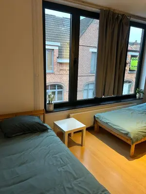 a bedroom with two beds and a large window at SiSEL HOUSE avaible with garden for 6 or more people! in Temse