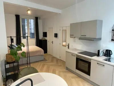 a kitchen with white cabinets and a bed in a room at Stadsstudio Antwerpen in Antwerp