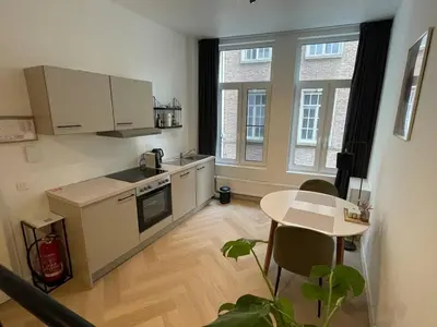 a kitchen with white cabinets and a table and window at Stadsstudio Antwerpen in Antwerp