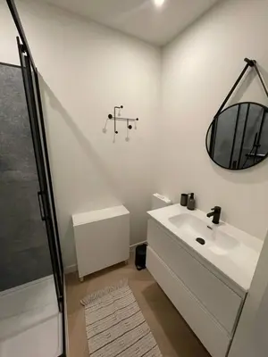 a white bathroom with a sink and a mirror at Stadsstudio Antwerpen in Antwerp
