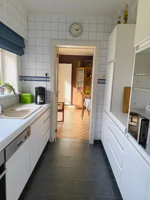a kitchen with white cabinets and a clock on the wall at Spelaan in Zottegem