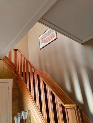a staircase with a wooden rail and a picture on the wall at Spelaan in Zottegem