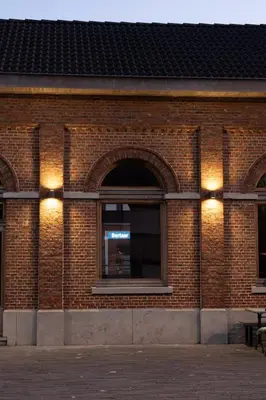 a brick building with two windows with lights on it at 't Spoor Berlaar in Berlaar