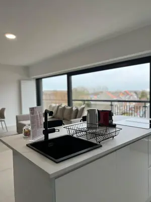 a kitchen counter with a sink and a living room at Luxury Apartment near Expo 12 & ING Arena & Atomium in Wemmel