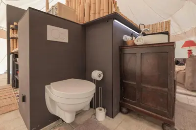 a bathroom with a toilet and a wooden cabinet at Tipi Bo exclusief in Kaprijke