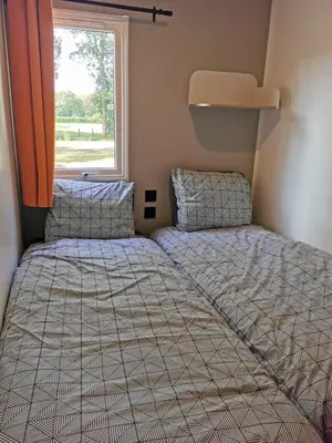 two beds in a small room with a window at Verblijfpark De Brem in Lille
