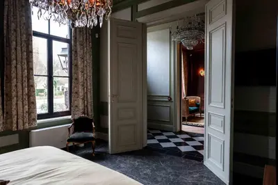 a bedroom with a bed and a window and a chandelier at Logies La Mairie in Waterland-Oudeman