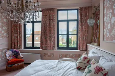 a bedroom with a bed and a chandelier and windows at Logies La Mairie in Waterland-Oudeman