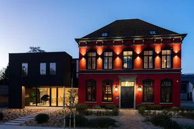 a red house with orange lights on it at Logies La Mairie in Waterland-Oudeman