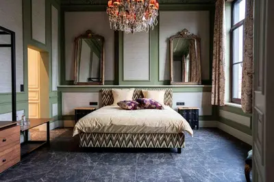 a bedroom with a bed with a chandelier and mirrors at Logies La Mairie in Waterland-Oudeman