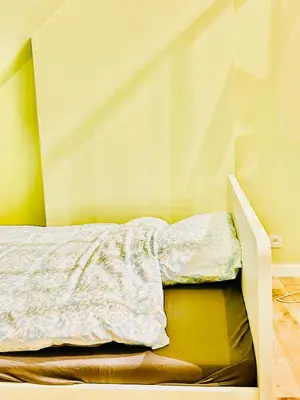 an unmade bed in a room with a wall at The Nest In Leuven - Family Friendly Room in Leuven