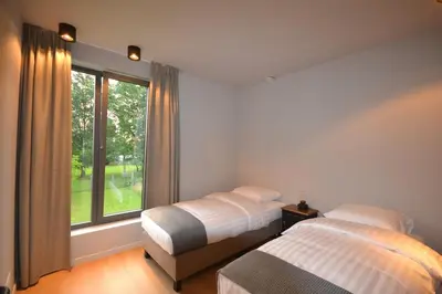 a bedroom with two beds and a large window at YOURhouse in Geel