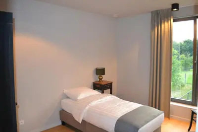 a bedroom with a bed with a window and a table at YOURhouse in Geel