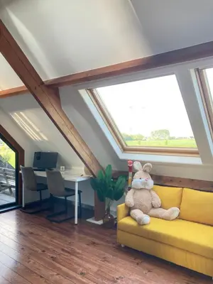 a teddy bear sitting on a yellow couch in a room with windows at Vakantiewoning centraal in België, veel privacy, prachtig uitzicht, airco in Denderleeuw