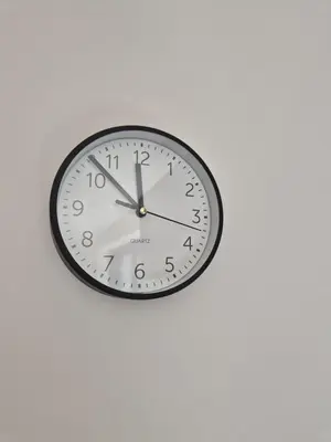 a clock is hanging on a white wall at Huis ALNA 6 in Mechelen