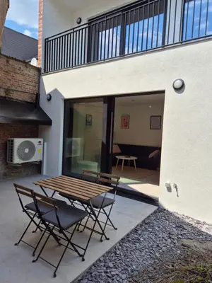 a patio with a wooden table and chairs next to a building at Huis ALNA 6 in Mechelen