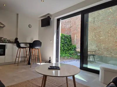 a living room with a table and a large window at Huis ALNA 6 in Mechelen