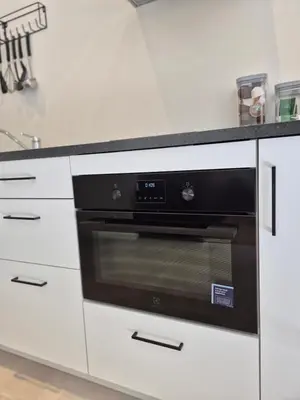 a black oven in a kitchen with white cabinets at Huis ALNA 6 in Mechelen