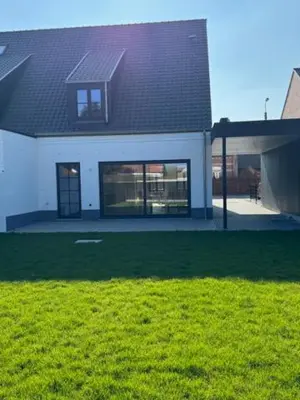 a white house with a black roof and a yard at Sœur in Berlare