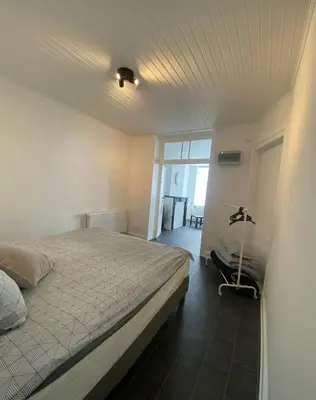 a bedroom with a bed and a room with a window at Grand appartement deux chambres in Brussels