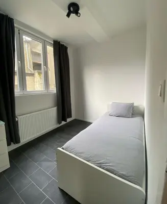 a bedroom with a bed and a window at Grand appartement deux chambres in Brussels