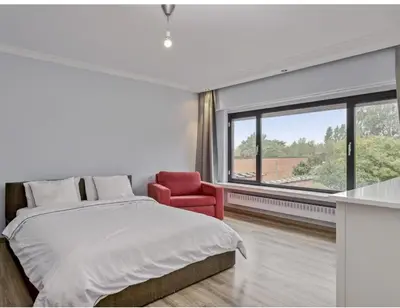 a bedroom with a bed and a red chair at Ngipe's Tomorrowland in Antwerp