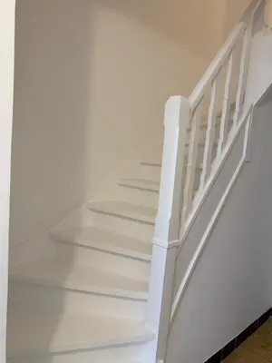 a white staircase with white railings in a house at Maison Agathe in Brussels