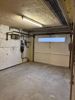 an empty garage with two garage doors and a window at Maison Agathe in Brussels