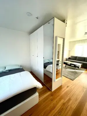 a bedroom with a mirror and a bed and a couch at Green Spot Meise - 15 min from Brussels with free parking & Self check-in in Meise