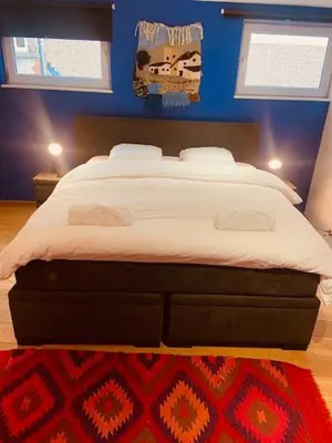 a large bed in a bedroom with a blue wall at Charming & Spacious Duplex viewing the lovely MAS in Antwerp