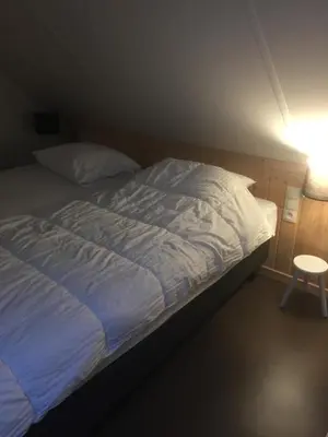 a bed with a blue and white comforter and a lamp at Luttelkolen in Holsbeek