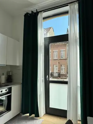 a kitchen with a large window with green curtains at MIDI cozy apartment in Brussels