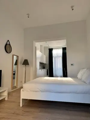 a bedroom with a large white bed and a mirror at MIDI cozy apartment in Brussels