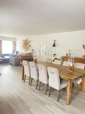a dining room with a wooden table and white chairs at MaïTyNa - Tomorrowland Stay in Rumst