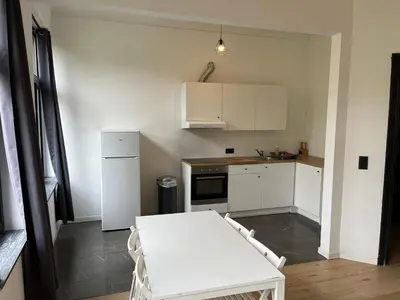 a kitchen with a white table and white cabinets at Flat south Brussels in Brussels