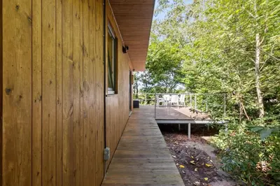 a wooden walkway next to a building with a bench at Chalet & Spa Nora in Stekene