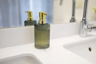 a green soap dispenser sitting on a bathroom sink at Apartment in the hyper-center in Brussels