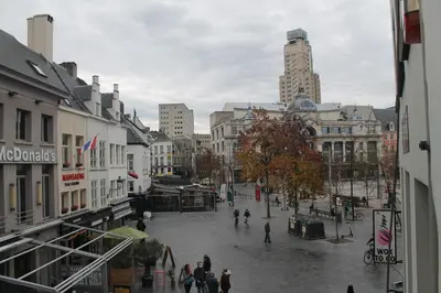 a city street with people walking around in the rain at The Antwerp Cathedral suite first floor in Antwerp