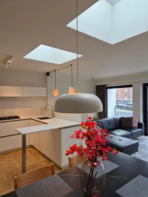 a kitchen and living room with a vase with flowers on a table at Huis ALNA 8 in Mechelen