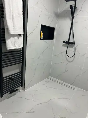a bathroom with a shower with white marble tiles at Villa op de hoek Rooms in Aalst