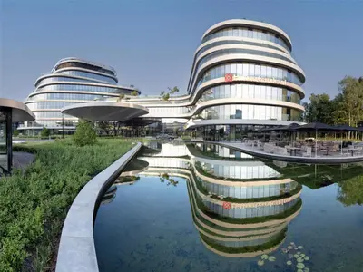 a building with a reflection in a body of water at Hilton Garden Inn Brussels Airport in Diegem